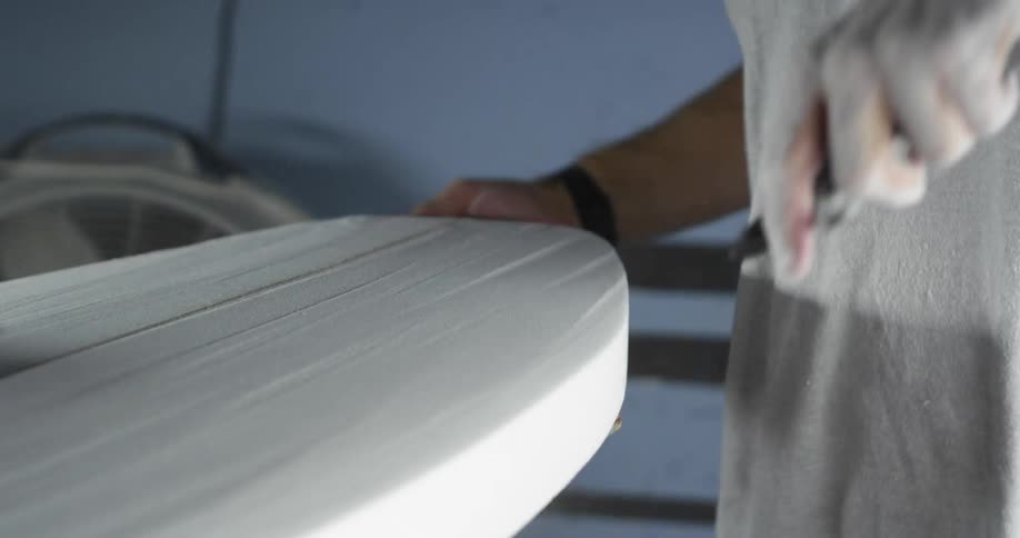 A man that is working on a surfboard in a shop