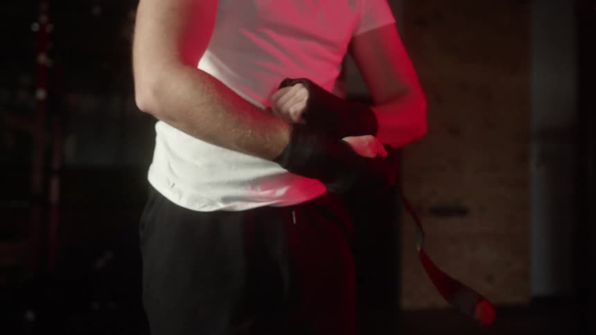 A person standing in a gym wrapping their hands with tape