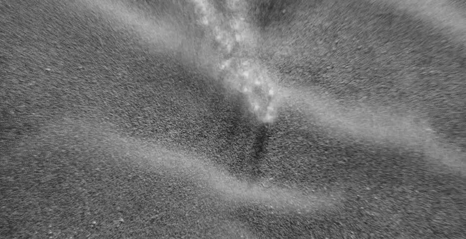 Birds eye view of bubbles in the water as it moves off the shore