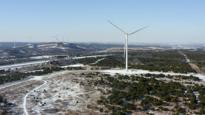 A wind turbine on a wind farm turns on a clear day