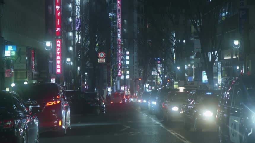 Cars moving in slow traffic in a city in japan at nighttime