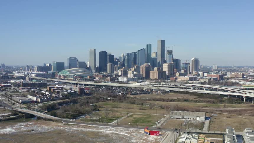 A city skyline with trees roads and buildings with the sky and clouds in the background