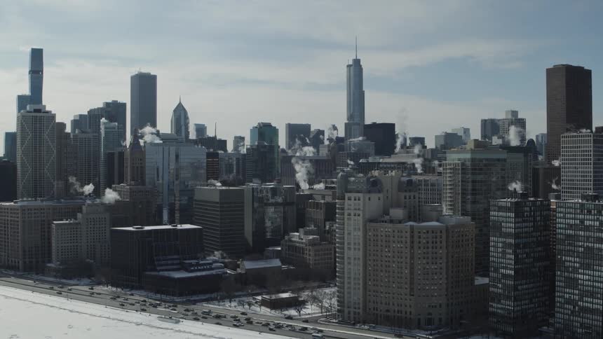 An aerial view of cars driving in front of skyscrapers and office buildings in a city