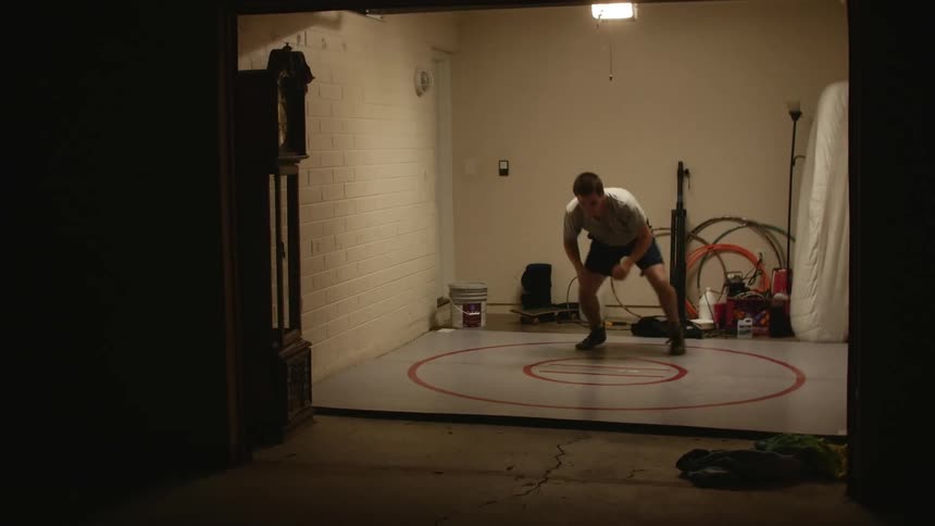 A man practices moves on a wrestling circle in a storage area