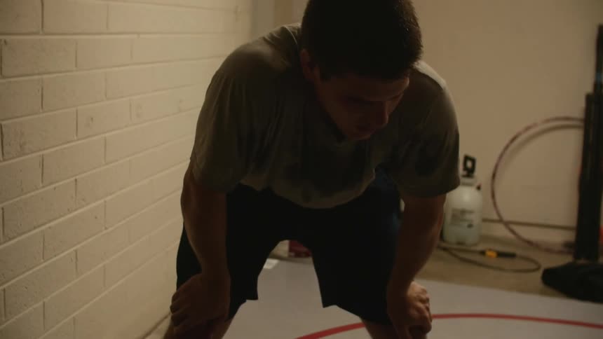 Tired young muscular man stretches inside a room