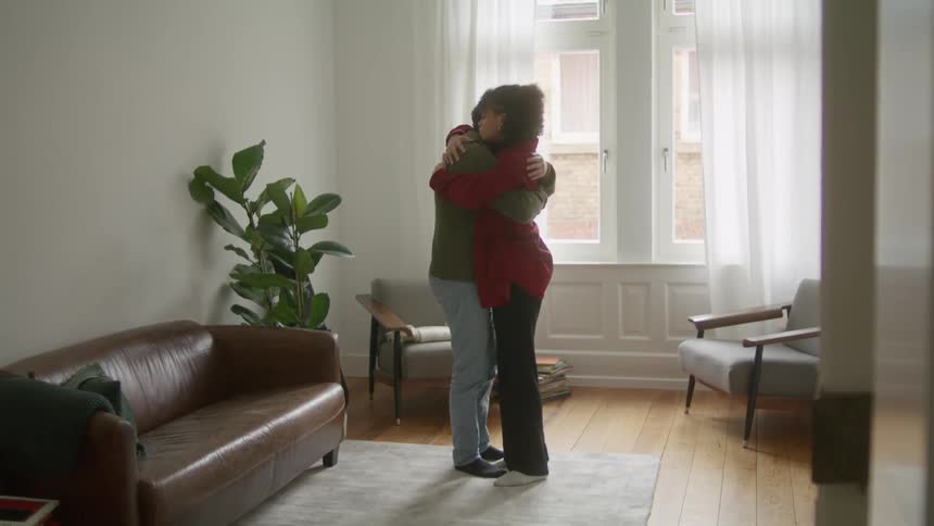 A man and woman hug in their living room