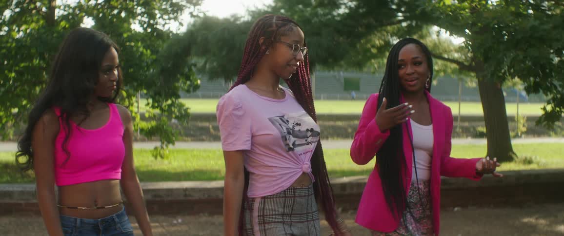Three teenage girls talk as they walk outside