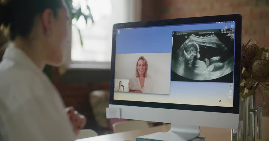 A doctor video chats on a computer with a woman as they look at an ultrasound