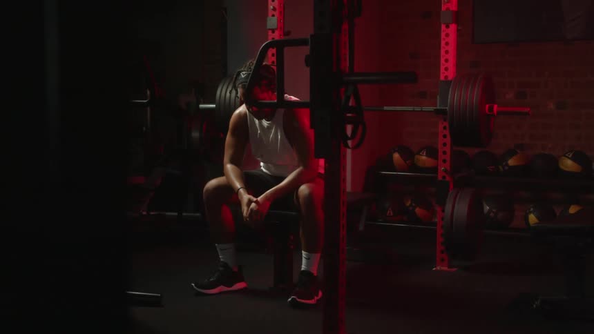 A man sits on a bench during a weight lifting session