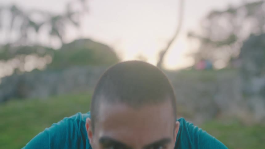 Young man doing push ups outdoors at sunset