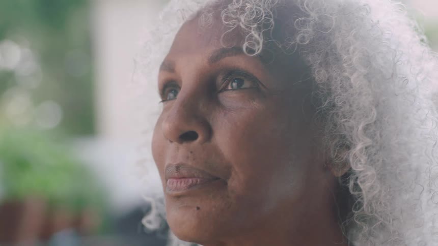 Woman with grey hair breathes and looks around happily in the garden