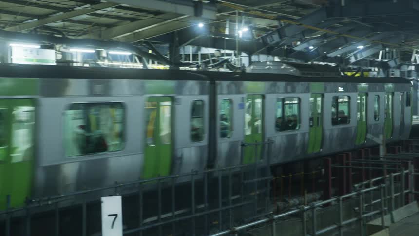 People sit on a train as it pulls through a station