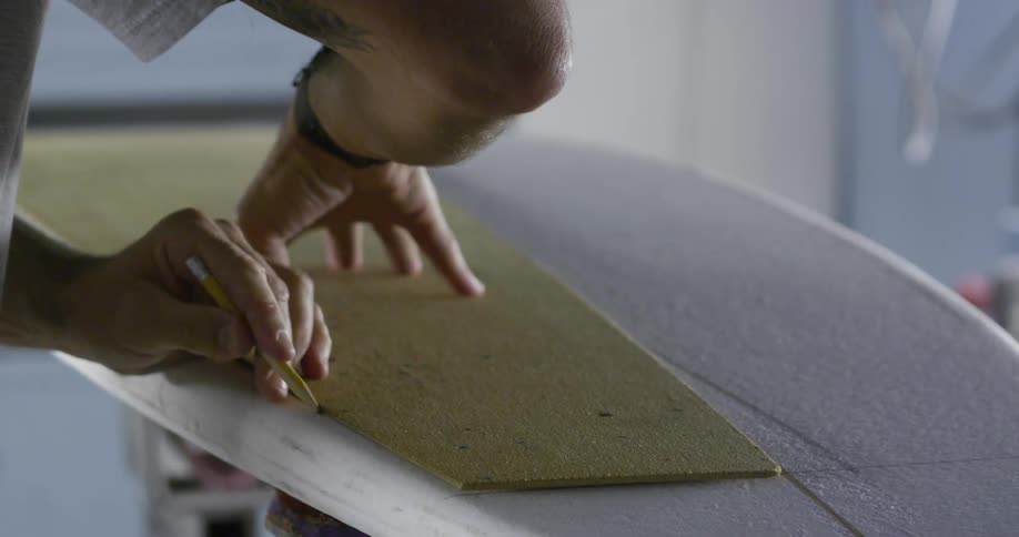 An employee draws on a surfboard
