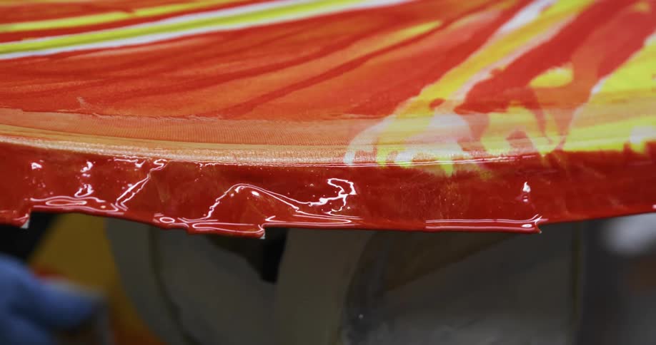 A person in a room with gloves painting a surfboard