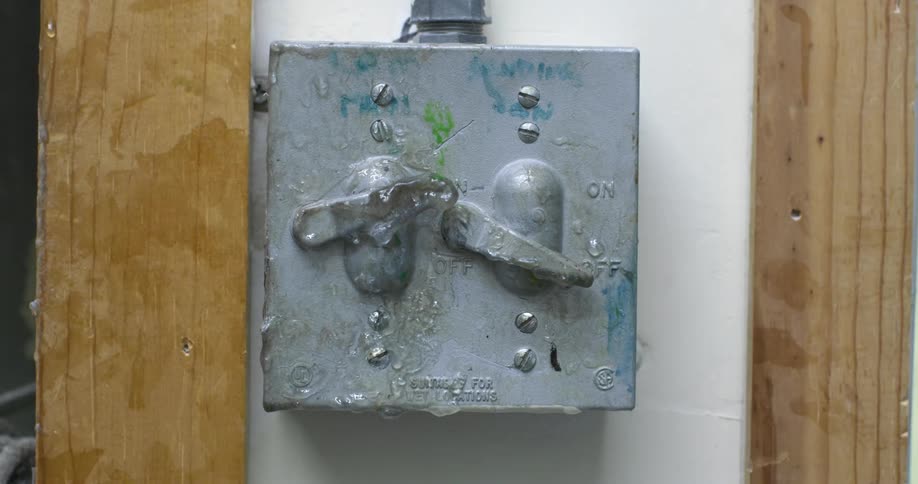 Hand wearing a glove flicking a vintage electrical switch on the wall