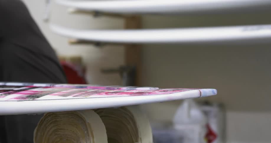 Man spreads mixture onto painted surfboard