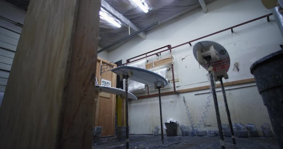 Surfboards sit on stands in workshop