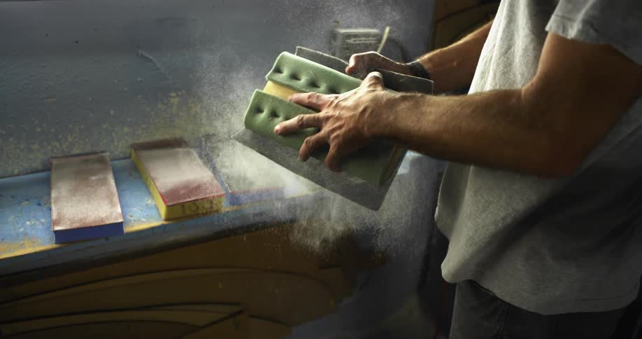 A man smacks a block on a towel and dust flies everywhere