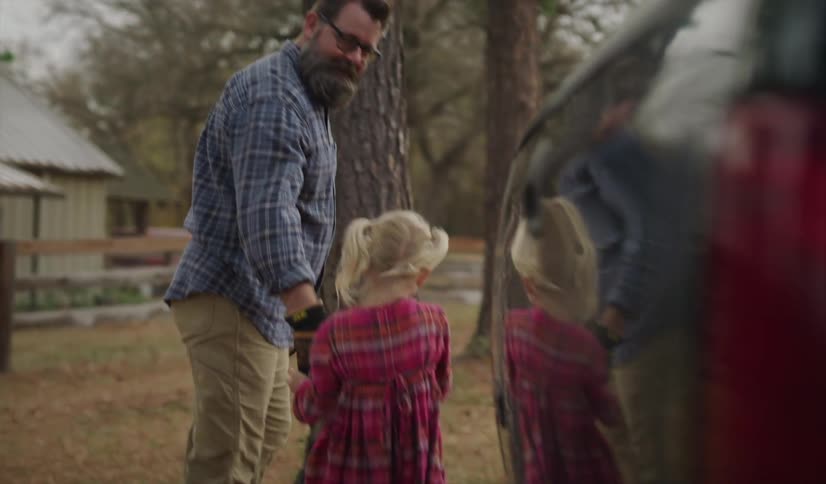 Father walking with his little daughters around a truck in a farm