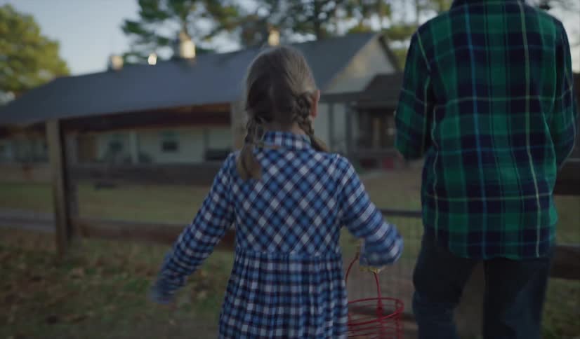 Brother and sister walk side by side while the sister carries a basket of chicken eggs and the brothers opens a wooden fence where a dog is waiting on the other side