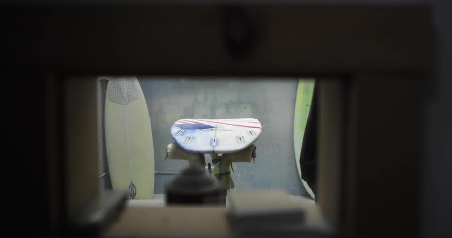 An employee working on a surfboard at a shop