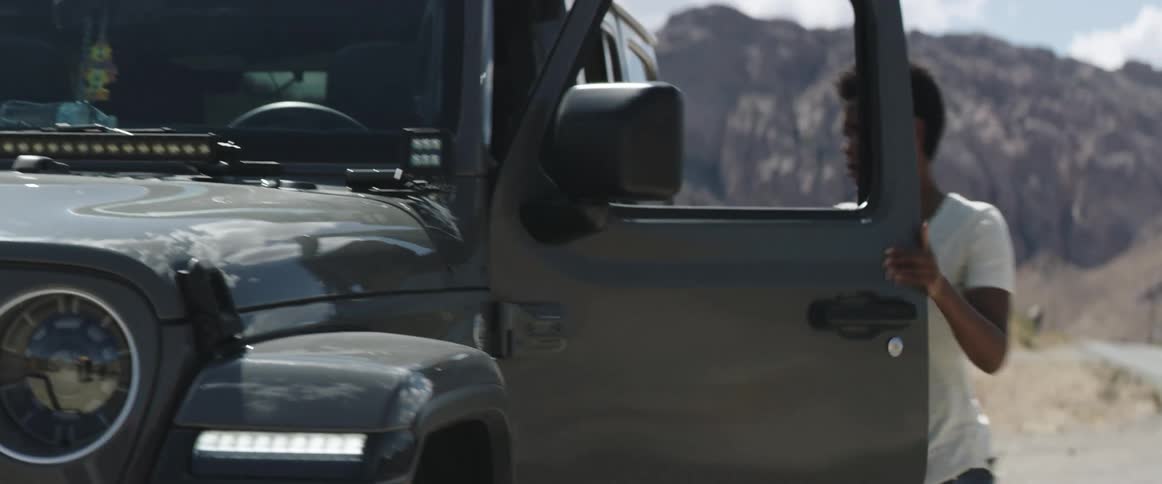 Young woman talking on the phone gets inside a car parked in a rural road in the mountains