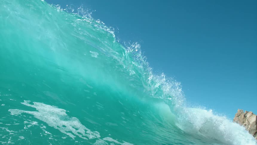 Big blue wave splashes as it rolls in