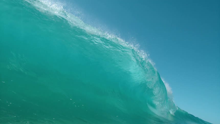 Big blue wave splashes and rolls overhead