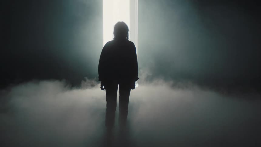 A model walks through thick fog on a stage