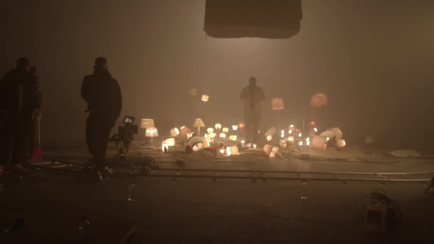 A film crew filming a scene with several lamps surrounding a person in a smoky dimly lit room