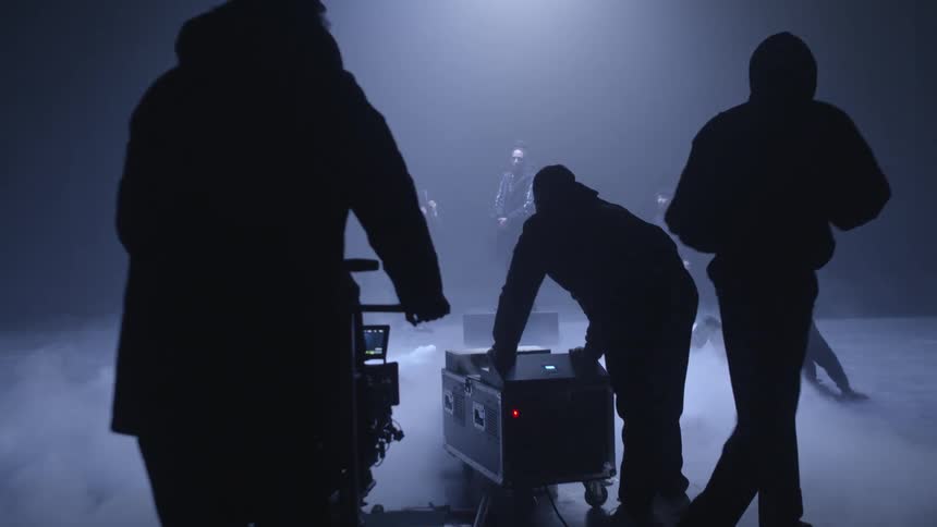 A person is pushing a smoke machine on the set