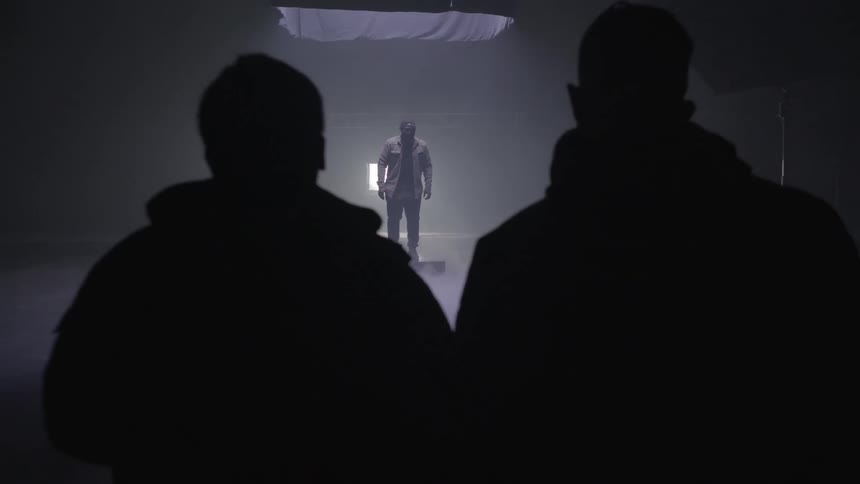 A view of a musician standing on a stage with two people looking