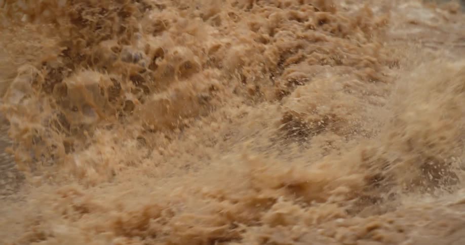 Slow motion shot of muddy sediment rich Colorado River whitewater churning and exploding deep in the heart of the Grand Canyon of the Colorado River