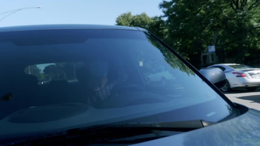 A man in a medical mask drives a vehicle along the roads of a town on a sunny day