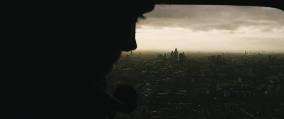 A silhouette of a person with a headset in an aircraft with a  London city skyline the sky and clouds in the background