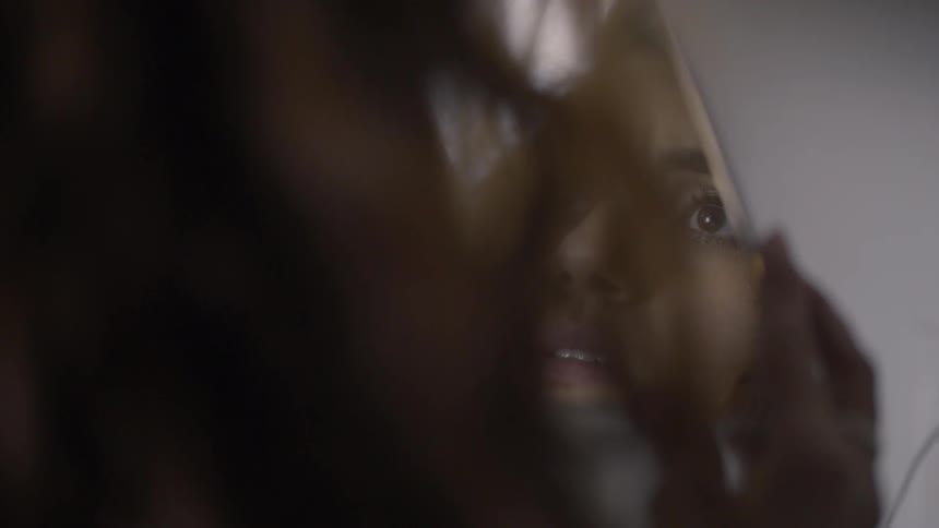A woman is looking at her reflection in a mirror