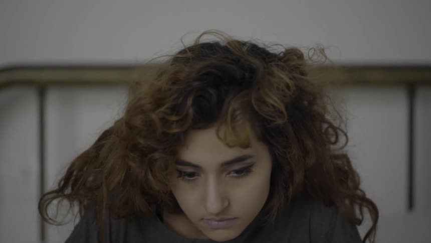 A sleepy woman rises up from her pillow in bed