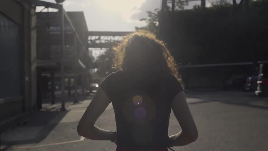 A woman walks through a parking lot in an industrial area