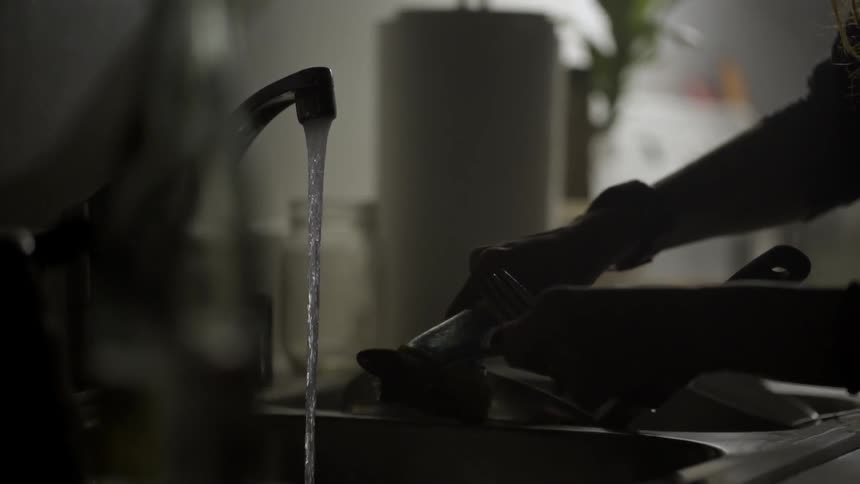 A person washes dishes in the sink
