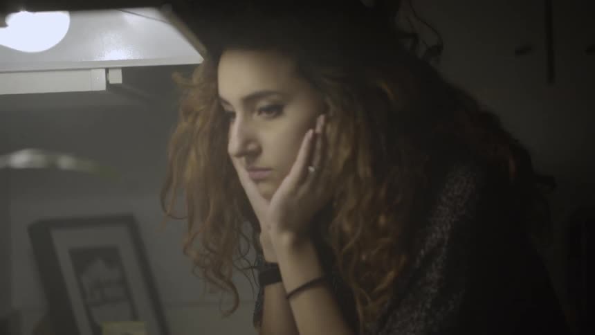 A woman leans forward and puts her head in her hands briefly