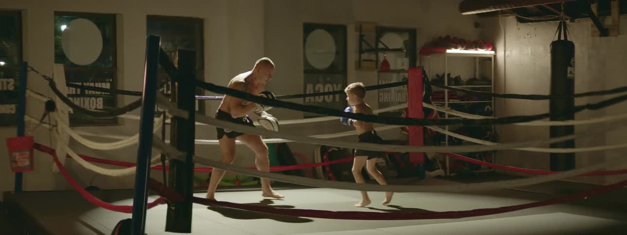 A father and son practicing boxing in a ring