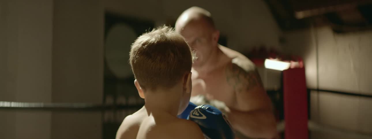 Man training a young boy sparring lessons in a boxing ring