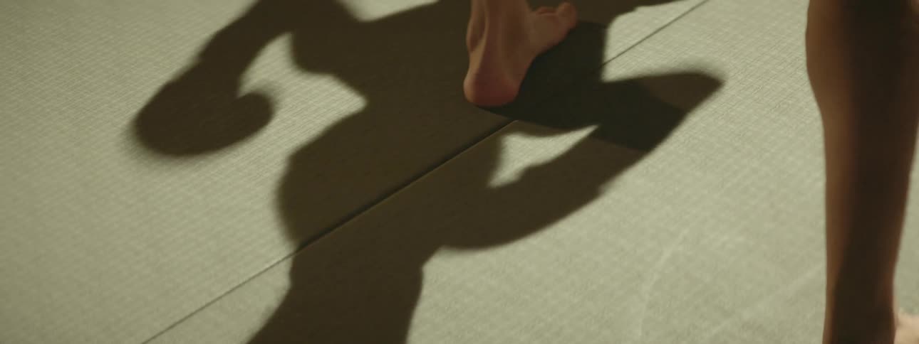 Shadows and feet of two people boxing in a ring