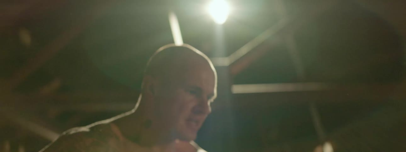 Man teaches child how to box in dark room with overhead lights