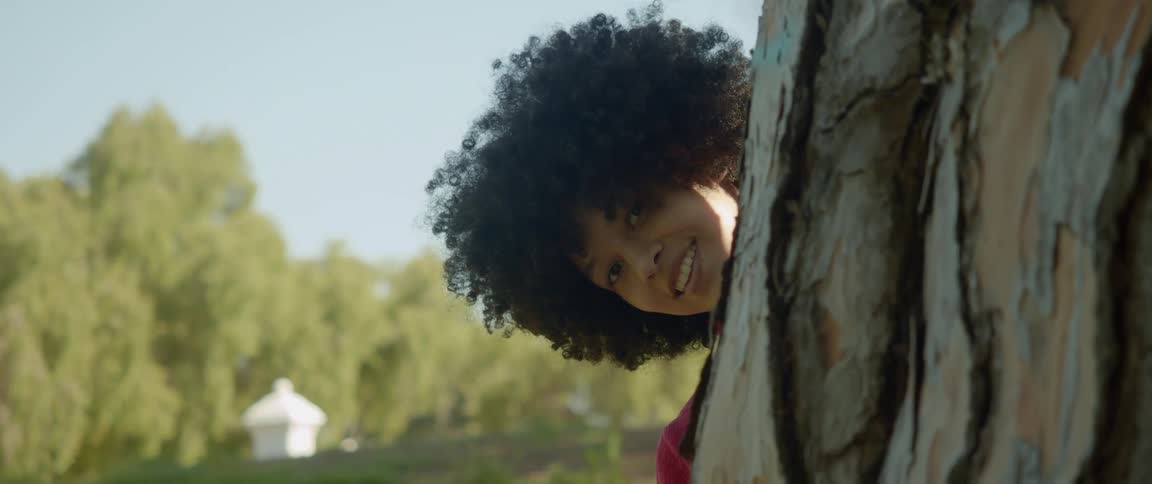 A woman is moving around the tree while smiling