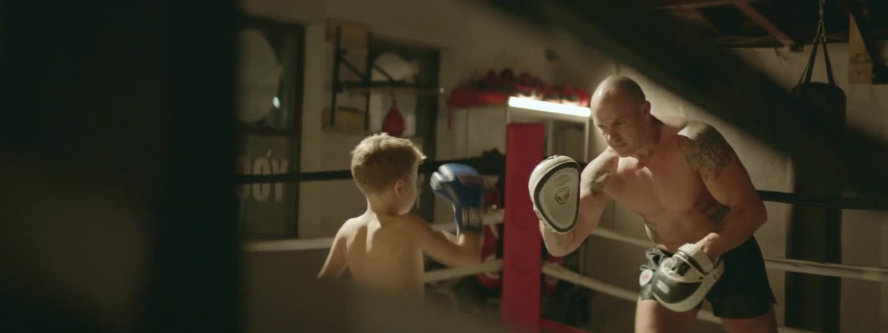 A man and a young boy box inside a boxing ring
