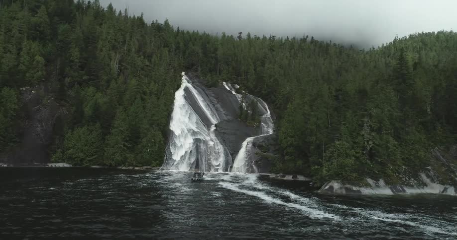 White water flows down a rock slope and onto the water where a boat sits