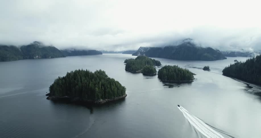 A boat sailing between the pine tree covered islands on a lake in the mountains