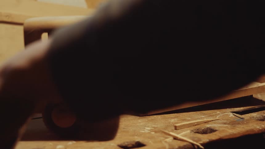 A man handcrafting wood toys inside a workshop