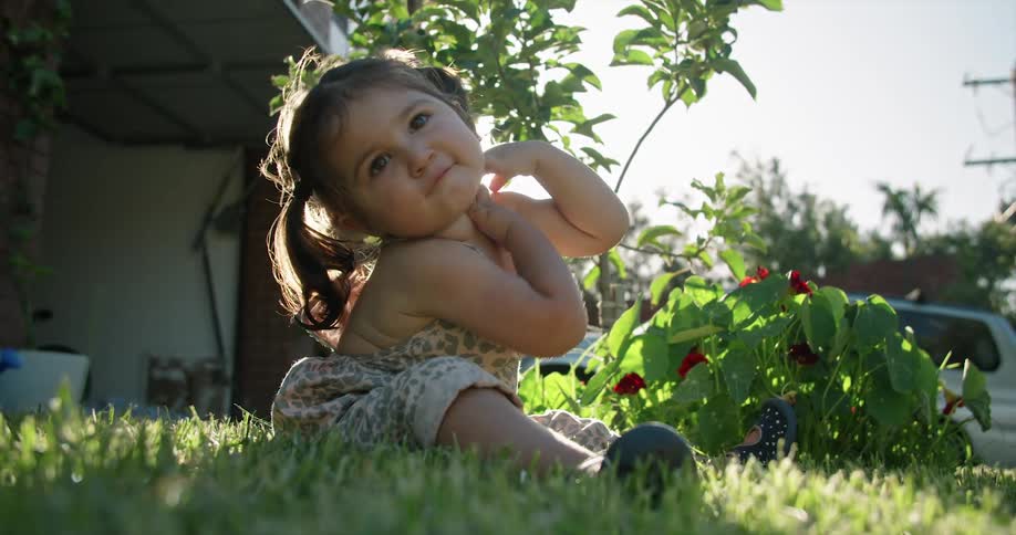 Girl sitting on the lawn next to a plant in the porch at morning